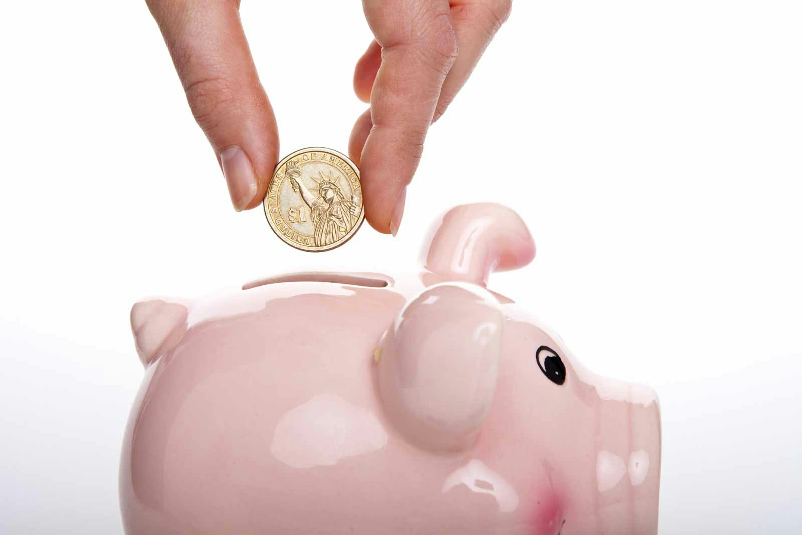 person putting a coin in a piggy bank
