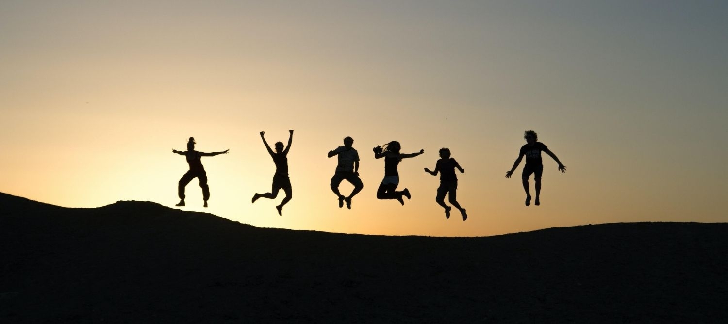 group of people jumping in the sunset