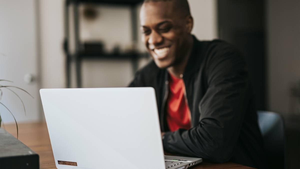 person smiling behind laptop computer